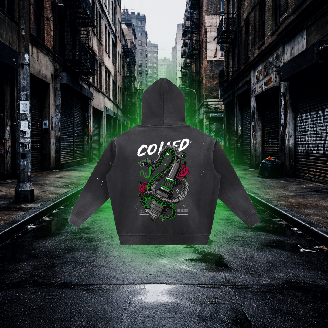 Black hoodie with graphic design and text on a neon green-lit urban street. Coiled Snake Graphic Hoodie – Premium Streetwear Animal Design Hoodie