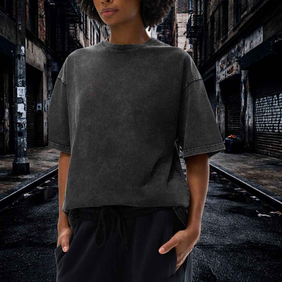 Person wearing a dark gray t-shirt and black pants in an urban alleyway.