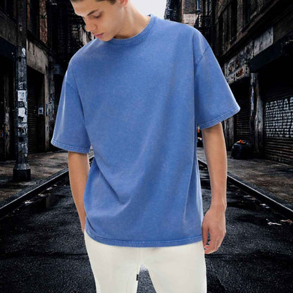 Person wearing a blue t-shirt standing on train tracks with an urban background