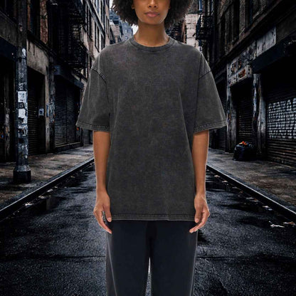 Person wearing a dark gray t-shirt and black pants standing in an urban alleyway.