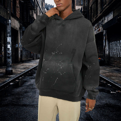 Person wearing a dark gray hoodie with splatter paint/vintage washed design in an urban alleyway. Samurai Street Beast Oversized Hoodie – Power Drift Car Streetwear Hoodie